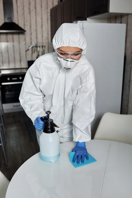 why-choose-us An individual disinfects a workspace using fumigation, wearing full protective gear for safety.